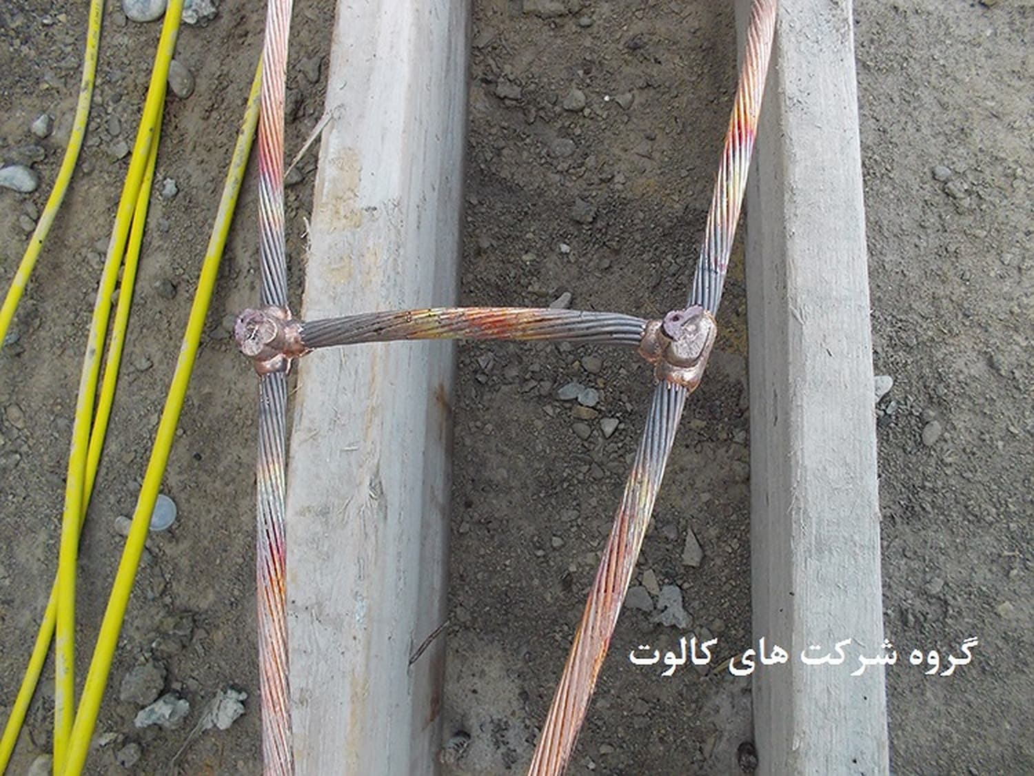 اتصال دو هادی مسی بافته‌شده با یک هادی رابط در کانال خاکی، کنار کابل‌های زرد