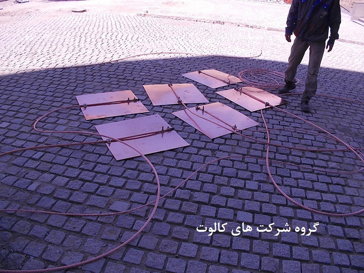 چند صفحهٔ مسی ارت با هادی مسی متصل، روی سنگفرش کنار یک تکنسین