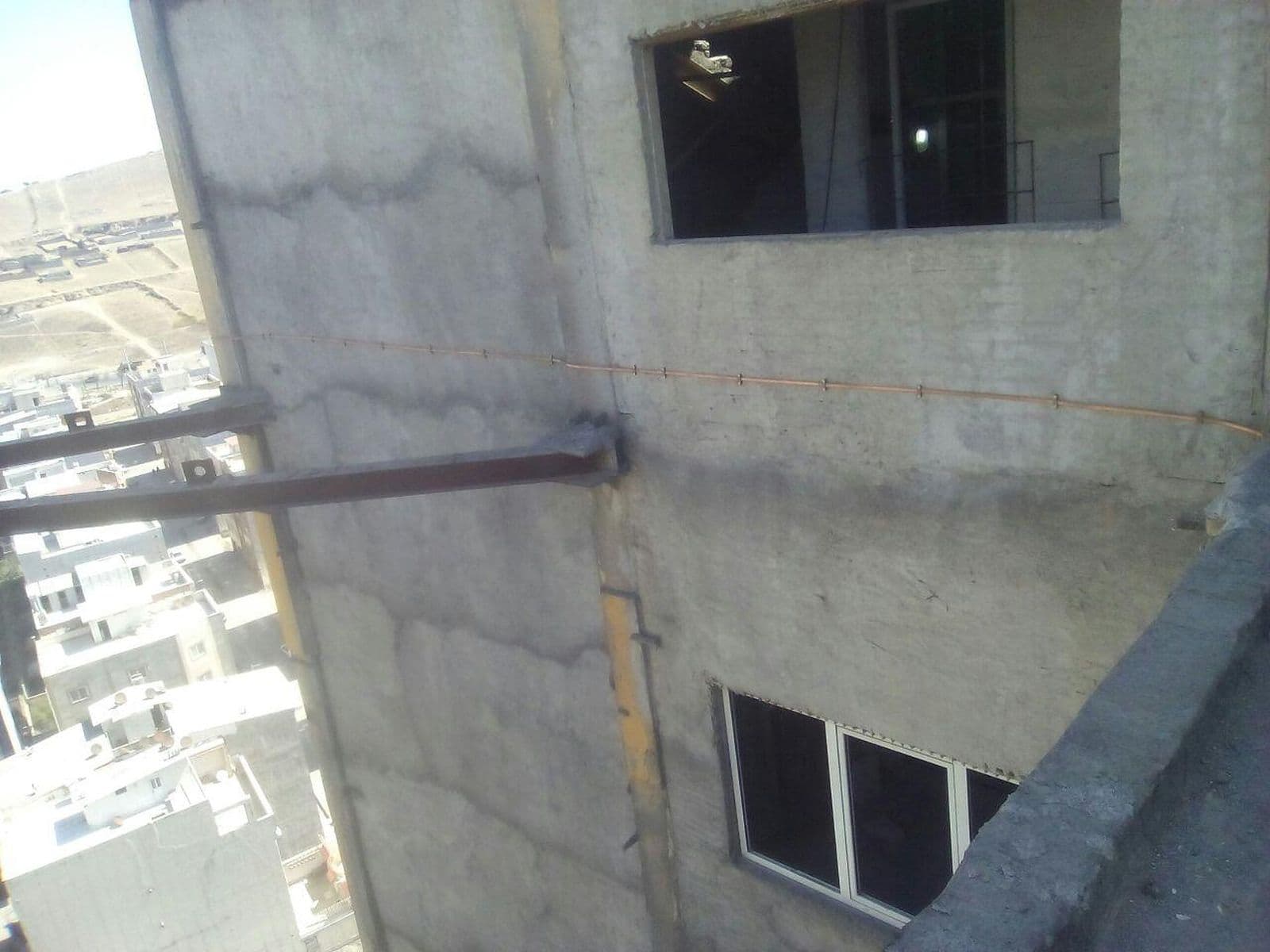 مسیر هادی روی دیوار بتنی بیرونی ساختمان در حال ساخت، کنار پنجره‌ها