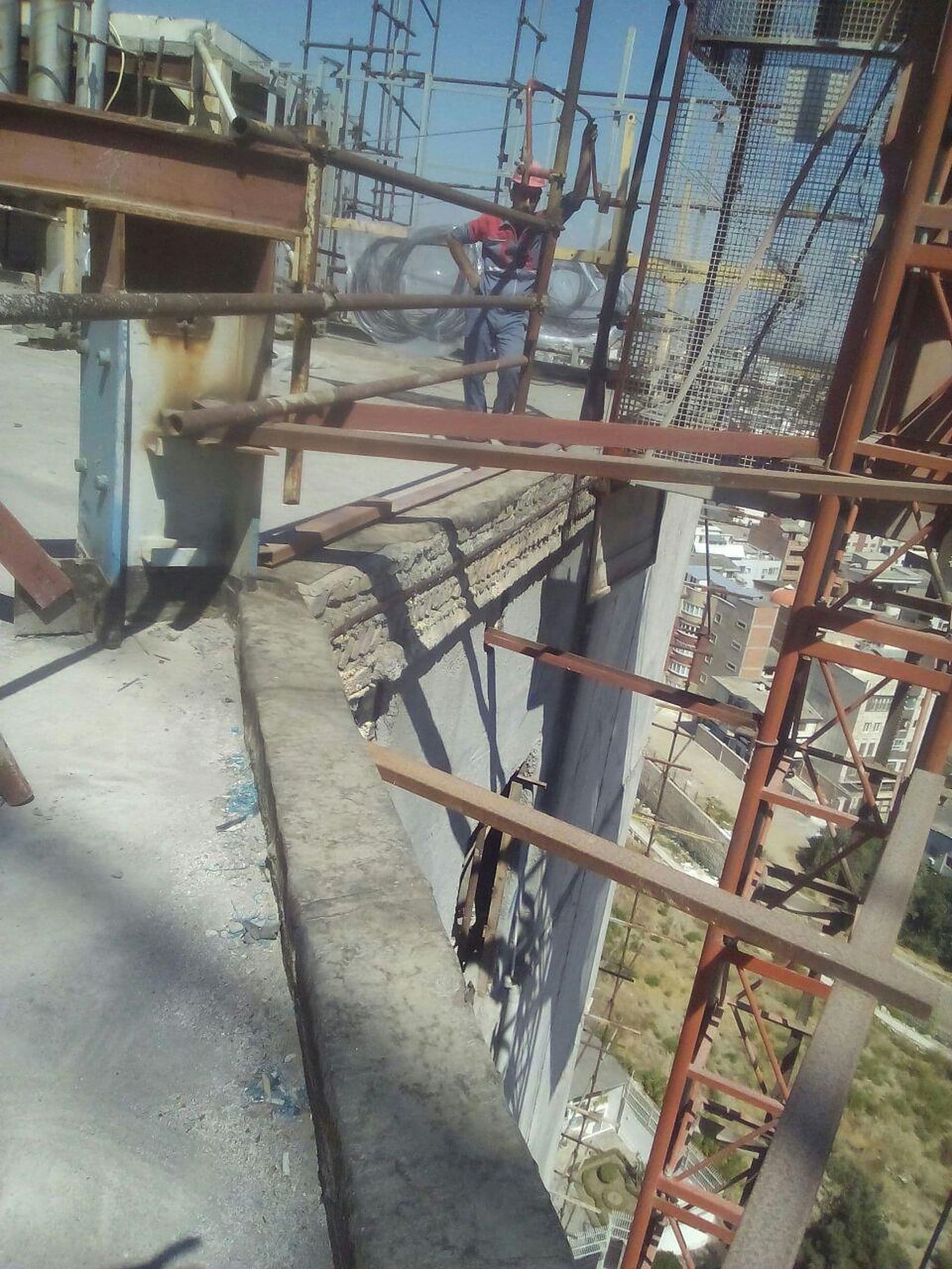 هادی کنار داربست و سازهٔ فلزی ساختمان در حال ساخت