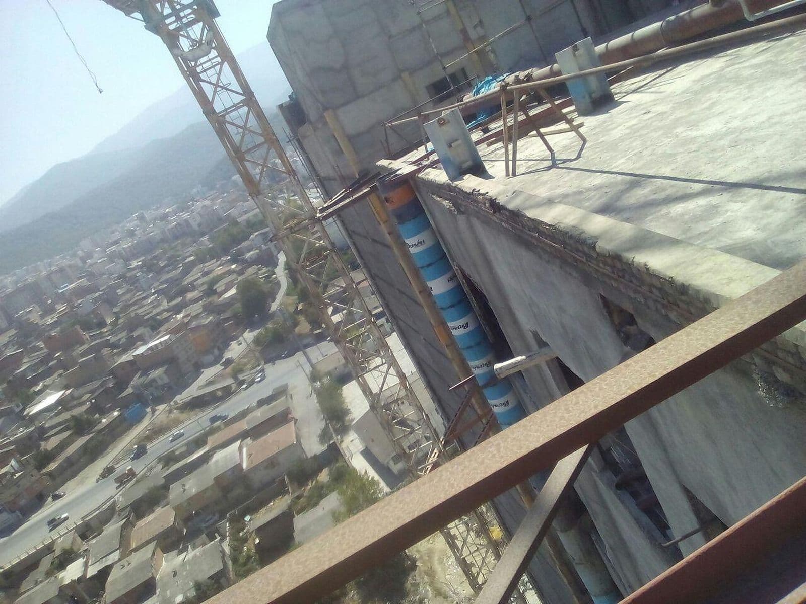 لبهٔ بام ساختمان بلند با جرثقیل برجی و شهر در پایین