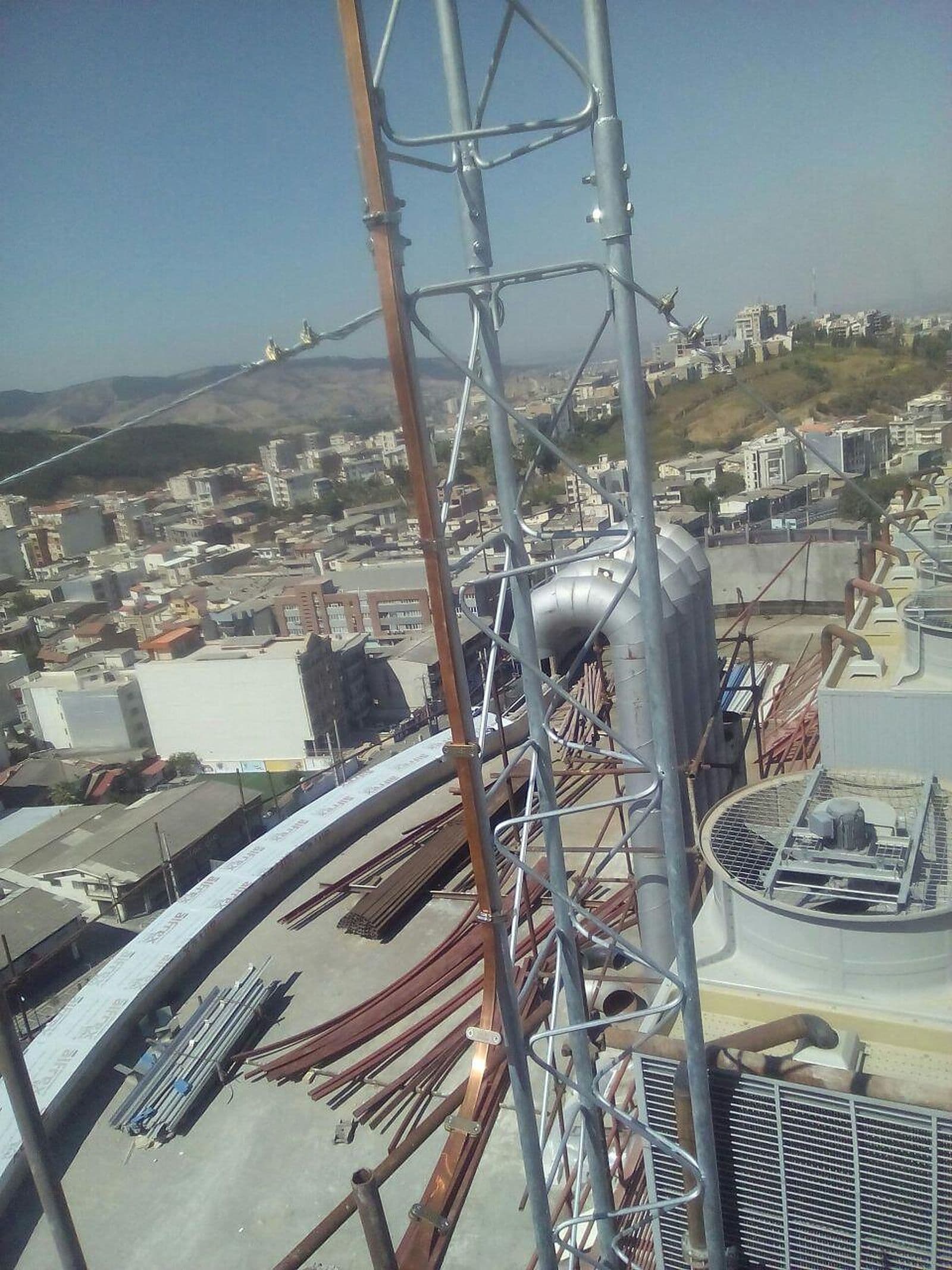 دکل مشبک بام با هادی در امتداد آن و نمای شهر در پایین