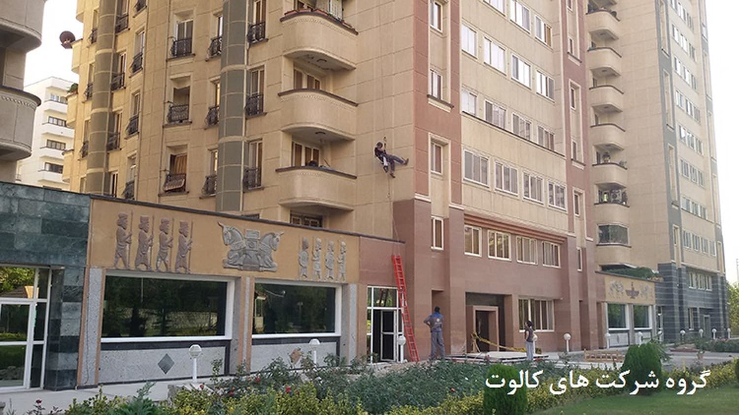 ساختمان مسکونی بلند با نمای آجری و تکنسین در حال کار روی نما