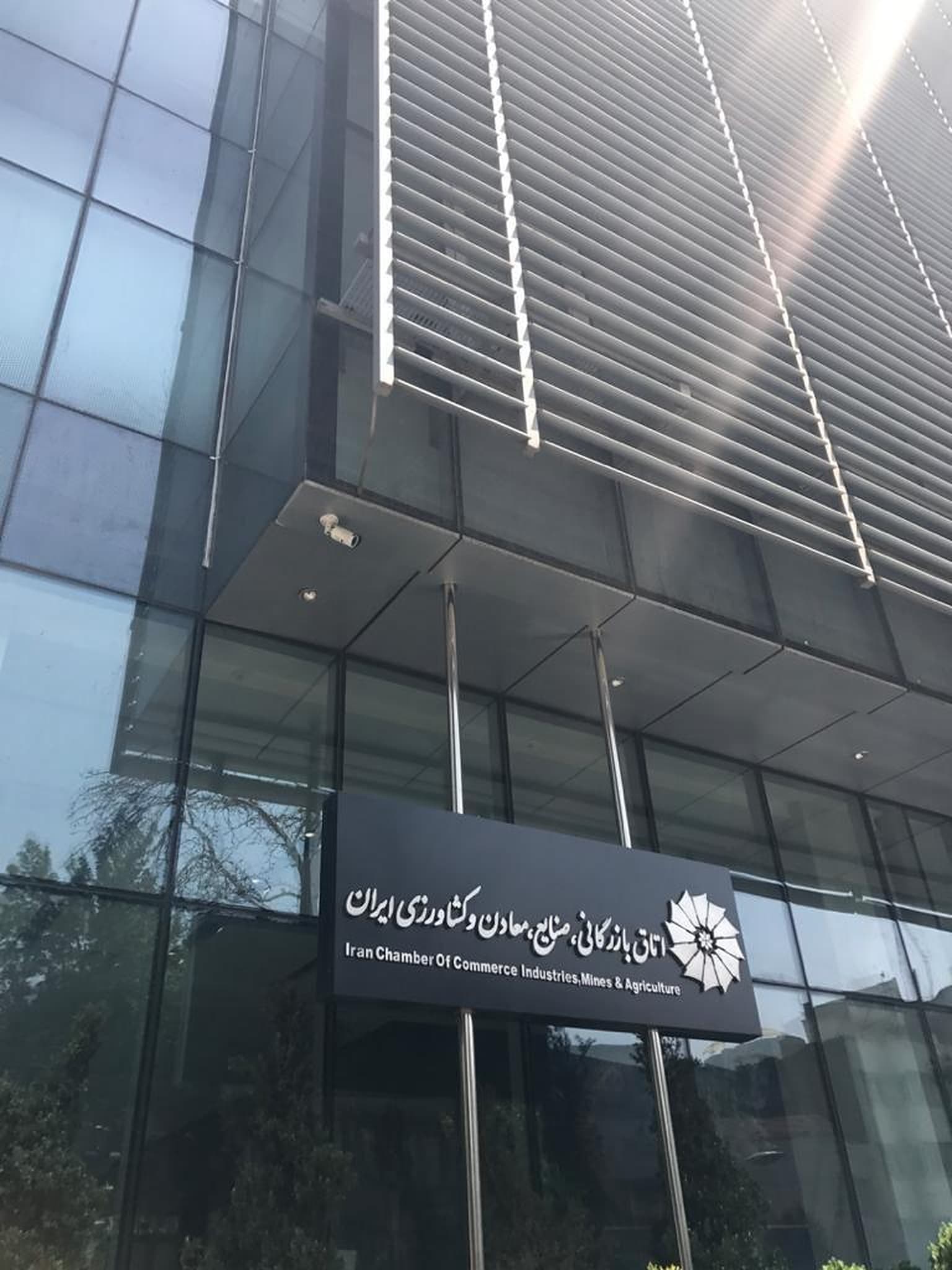 ورودی ساختمان اداری با نمای شیشه‌ای و تابلوی سازمان