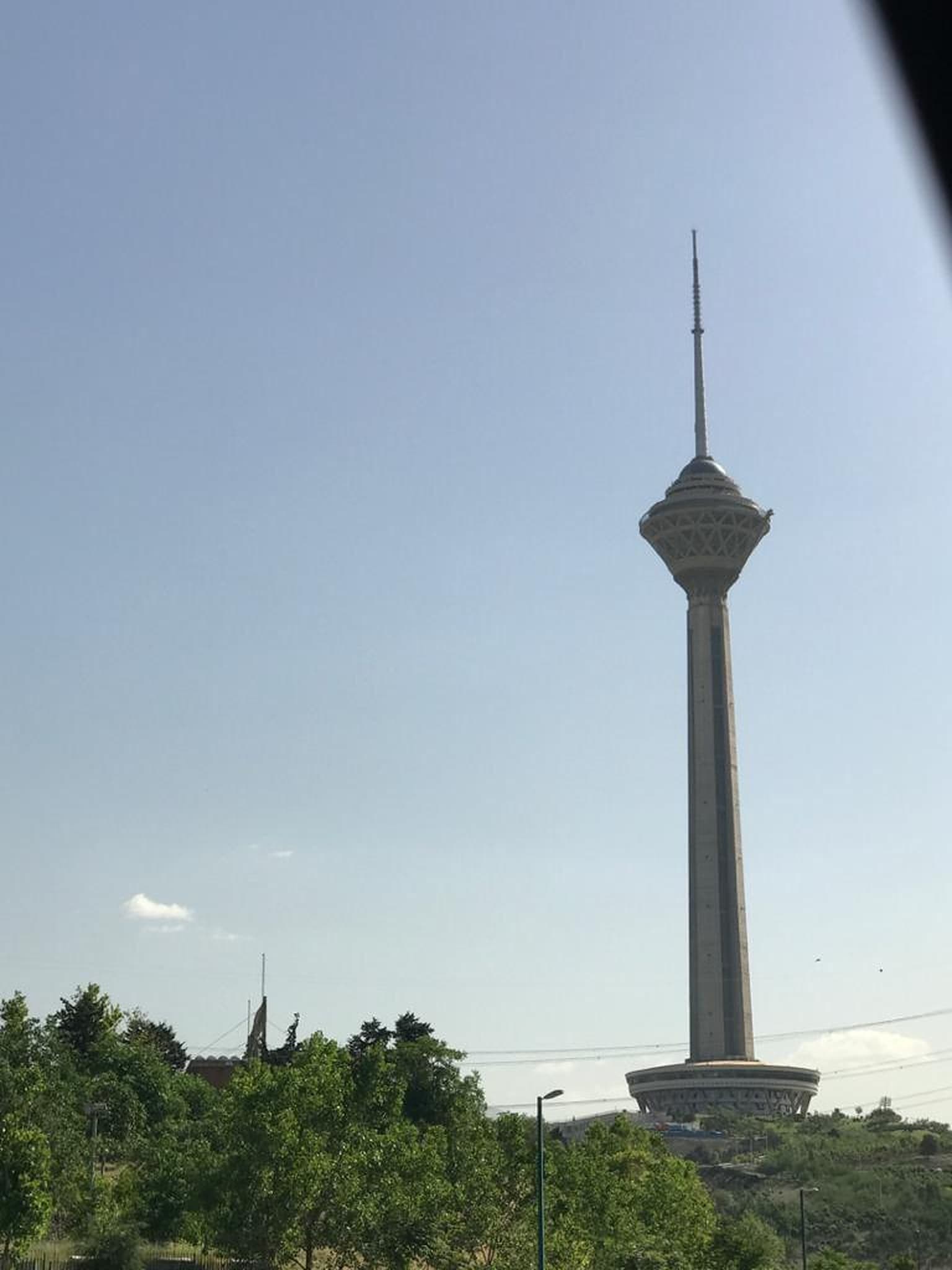 برج میلاد تهران میان درختان در روز آفتابی
