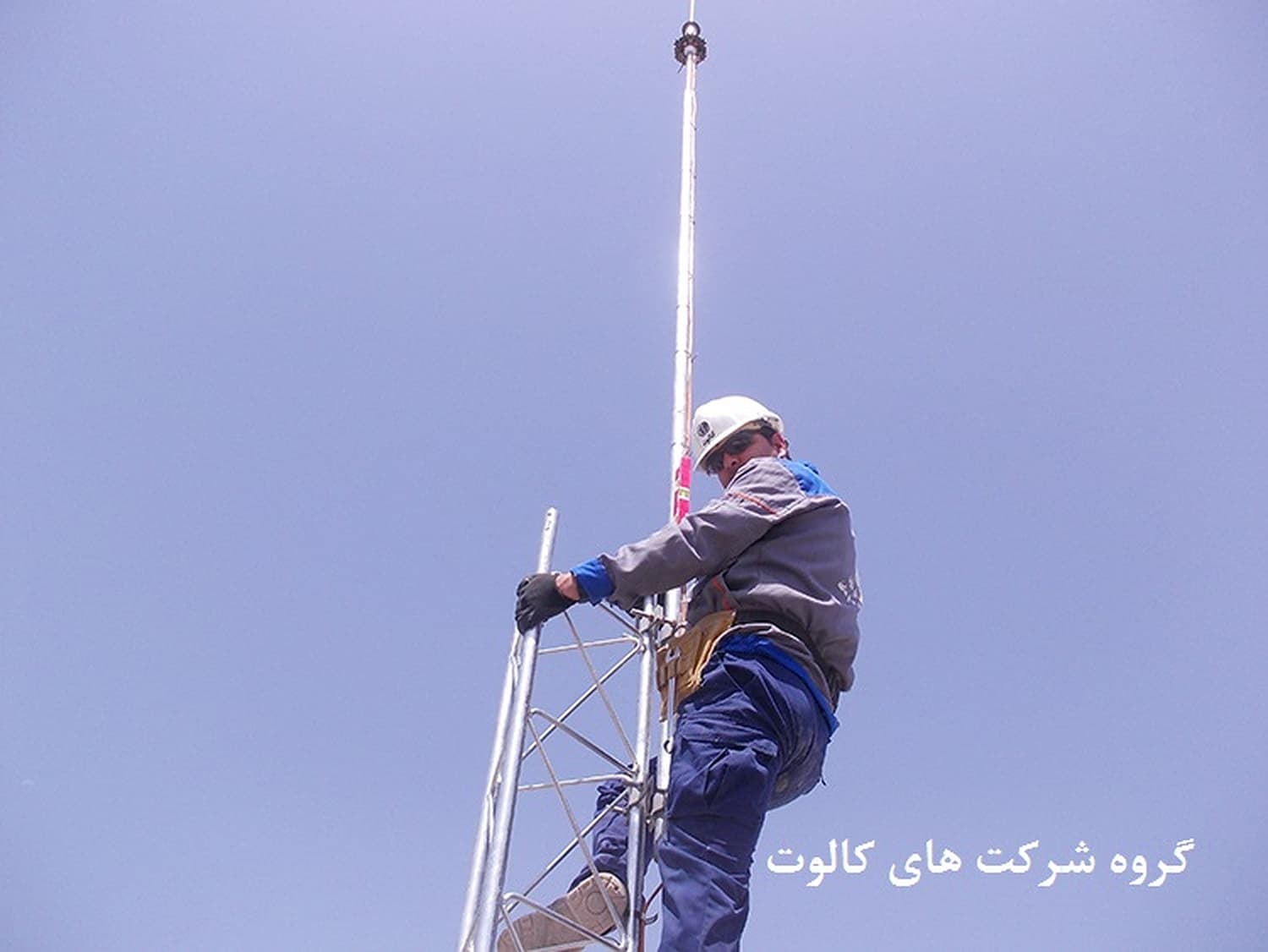 تکنسین با کلاه ایمنی روی دکل مشبک در حال نصب صاعقه‌گیر الکترونیکی