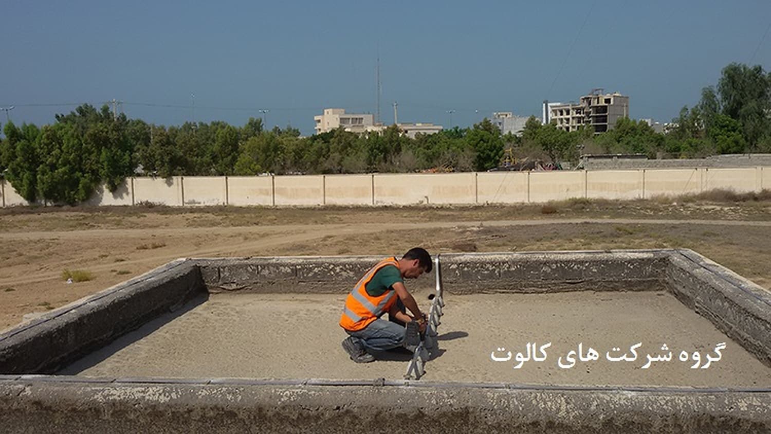 تکنسین با جلیقهٔ نارنجی در حال کار در چالهٔ مستطیلی شبکهٔ زمین