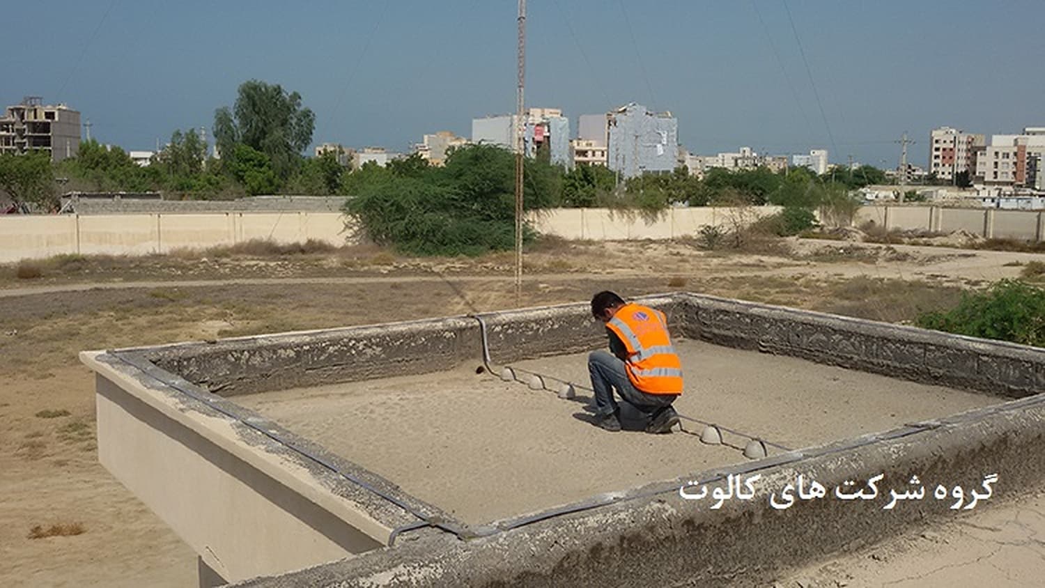 تکنسین در کف چالهٔ شبکهٔ زمین با دکل در پس‌زمینه