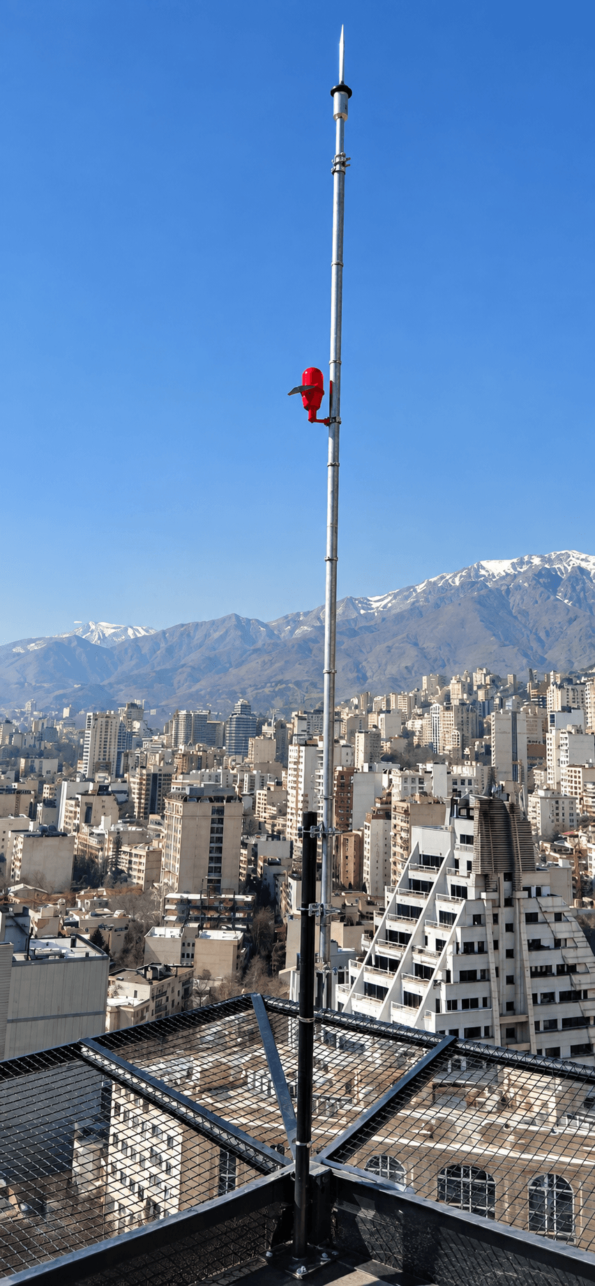 صاعقه‌گیر الکترونیکی نصب‌شده روی دکل بام با نمای شهری و کوهستانی