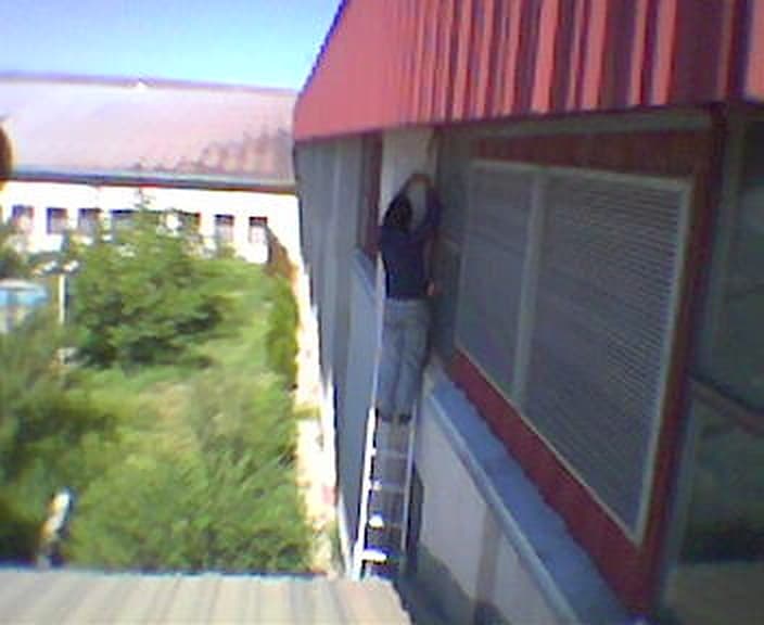 تکنسین روی نردبان کنار دیوار ساختمان کارخانه